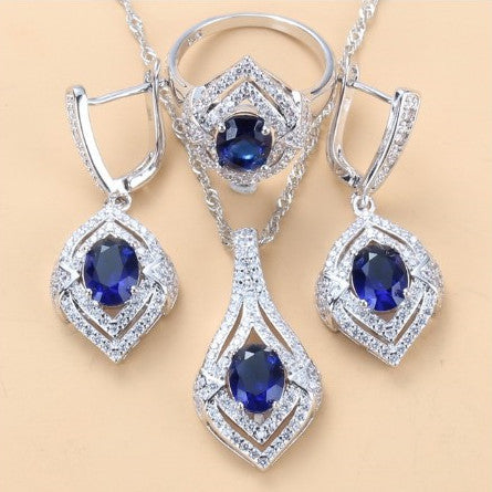 Silver-toned three-piece jewelry set with clear oval and round gems, including a necklace, dangle earrings, and a ring. - Image 7