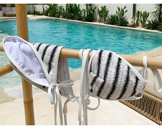 White and black striped bikini with triangle-cut top and tie-side bottom, modeled outdoors. - Image 21