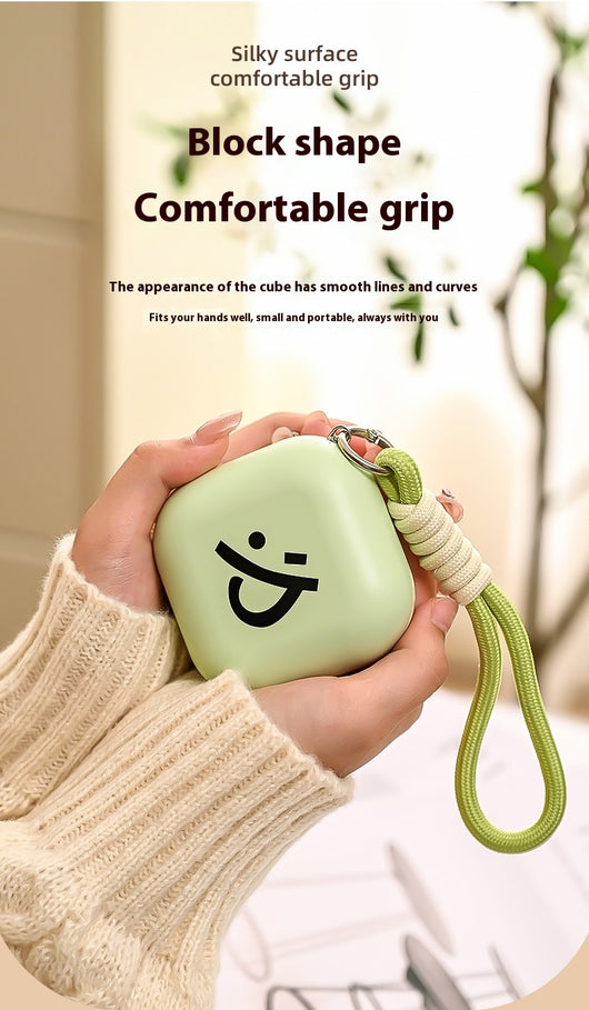 Light green square hand warmer with rounded corners and a black smiley face, hanging from a two-tone lanyard. - Image 12