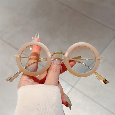 Small frame oval fashion sunglasses with black frames and vibrant orange lenses, held by a hand. - Image 22