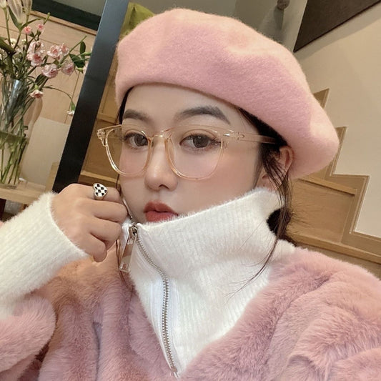 Retro square transparent full-frame glasses with blue light lenses, held by a person wearing grey sweatpants.