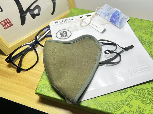 Dark gray cotton head-mounted mask with adjustable ear loops, shown in packaging on a patterned green surface. - Image 21