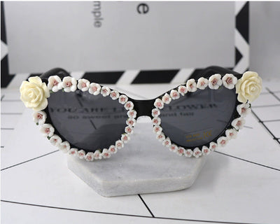 Black cat-eye sunglasses with dark lenses, adorned with small red rose embellishments along the frames. - Image 7