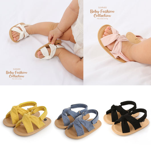 Black baby sandals with knotted cross straps and a matching black floral headband on a white background. - Image 2