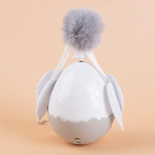 Electronic cat motion toy, a white and grey tumbler ball with fluffy pom-pom and soft wings, next to its retail box. - Image 6