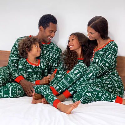 Family of four wearing matching green and white Christmas pajamas with fair isle print and red trim, sitting on a bed. - Image 2