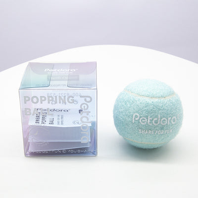 Peach yellow Petdora high elastic tennis ball dog toy next to its clear iridescent 'Popping Ball' packaging. - Image 3