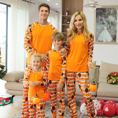 Family of four wearing matching orange and white striped Halloween pajamas with pumpkin and bat prints. - Image 4