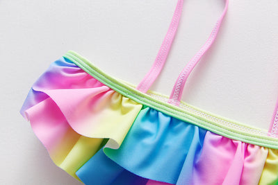 Children's rainbow tie-dye bikini set with a ruffled top and side-tie bottoms, perfect for summer swimming. - Image 13