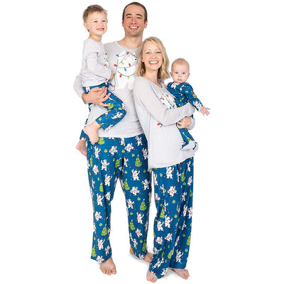 Family of four wearing matching Christmas pajamas with polar bears, string lights, and Christmas trees. - Image 13