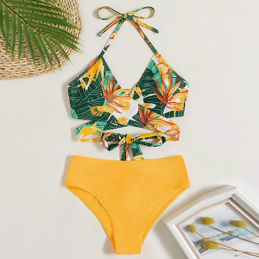 Women's two-piece swimsuit with a green, yellow, and orange tropical floral print halter top and solid yellow high-waisted bikini bottoms.