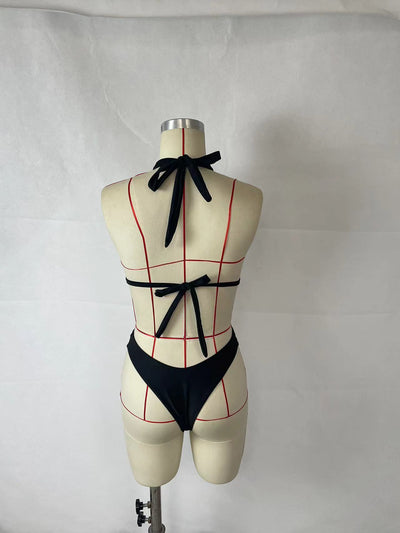 Woman wearing a black two-piece halter bikini with a cut-out detail and high-cut bottoms, leaning on a stone wall. - Image 7