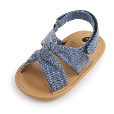Black baby sandals with knotted cross straps and a matching black floral headband on a white background. - Image 25