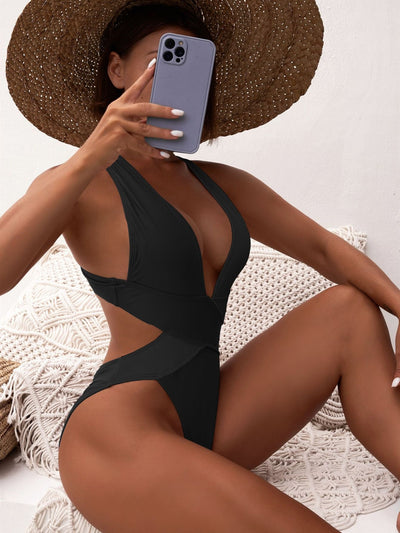 Woman in a black one-piece swimsuit with a deep V-neck and criss-cross waist cutouts, wearing a straw hat. - Image 12