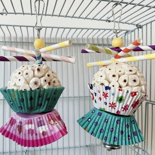 Two parrot shredding toys, shaped like cupcakes with paper straws, featuring colorful paper cups and a metal clasp.