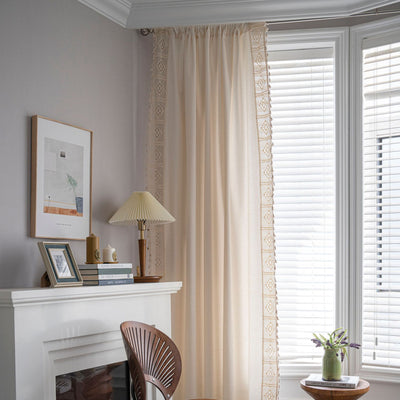 Close-up of a beige semi-transparent curtain with a delicate crochet lace trim and decorative tassels. - Image 2