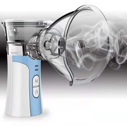 Hand-held compression atomizer with a clear mask and white and blue body, emitting a fine mist.