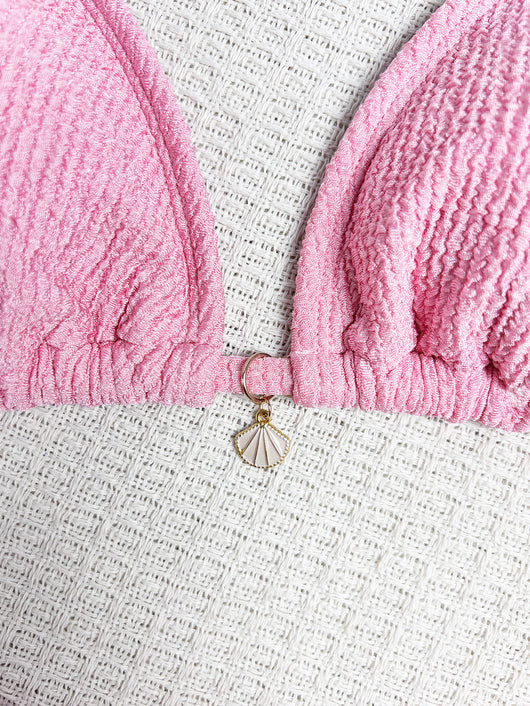Pink textured halter bikini swimsuit with gold beads and a shell charm, worn by a woman on a wooden surface. - Image 14