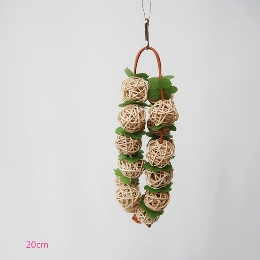 Pink woven rattan ball parrot chew toy with green leaf accents, hanging from a metal hook. - Image 8