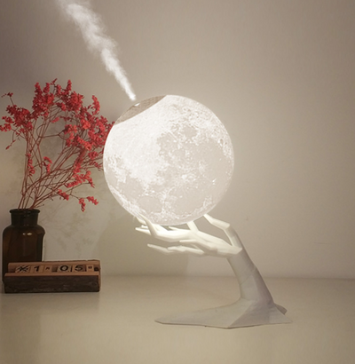 Moon-shaped humidifier and night light with a white deer stand, emitting mist, on a wooden table with books. - Image 10