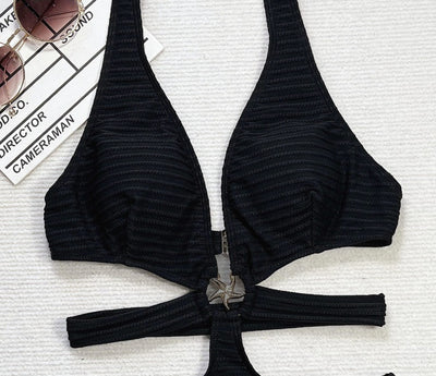 Woman in a black ribbed one-piece swimsuit with a halter neck, side cut-outs, and a starfish ring detail, lying on a white towel. - Image 15