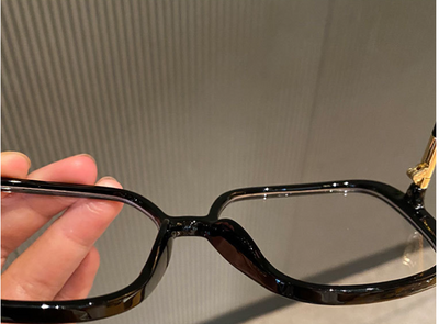 Black oversized square anti-blue light glasses with clear resin lenses and gold metal frame details, held by a hand. - Image 11
