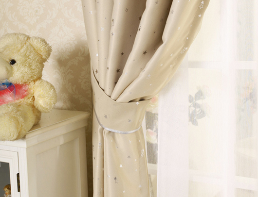 Blue star print curtains tied back to reveal sheer white curtains, in a bright room with a white chair. - Image 5