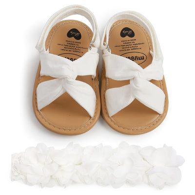 Black baby sandals with knotted cross straps and a matching black floral headband on a white background. - Image 10