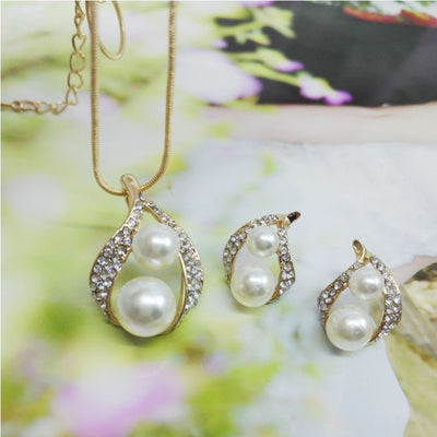 Gold-tone teardrop necklace and matching stud earrings set with white pearls and clear rhinestones, displayed on black. - Image 7
