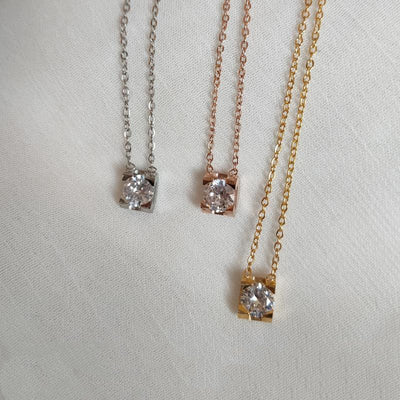 Delicate silver-colored chain necklace with a single square-cut clear stone pendant in a four-prong setting on a woman's neck. - Image 13