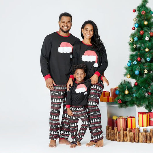 Family of three wearing matching black Christmas pajamas with Santa hat tops and reindeer fair isle pants. - Image 3