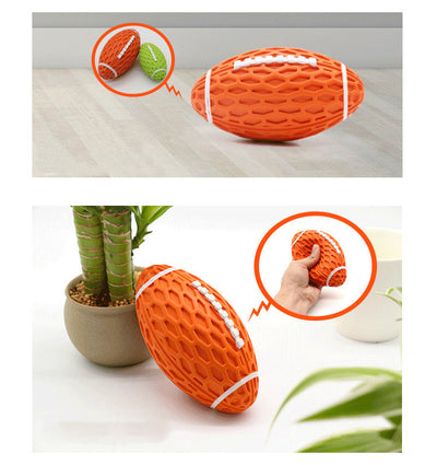 Orange rubber rugby ball dog toy with honeycomb texture and white laces, being squeezed by a hand. - Image 8