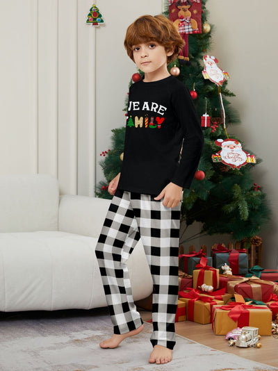 Family of four wearing matching black long-sleeve pajamas with "WE ARE FAMILY" text and black and white plaid bottoms. - Image 16