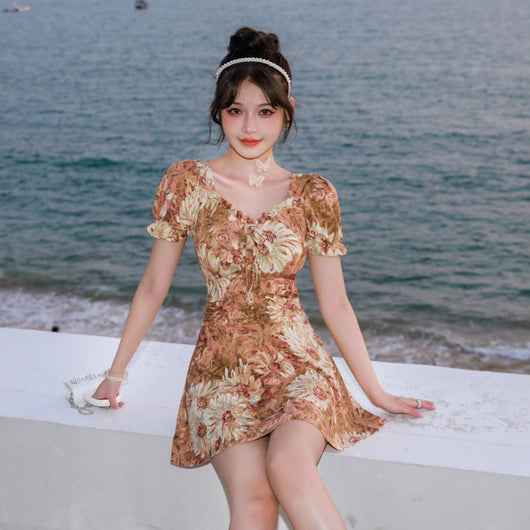 Woman in a blue and pink floral print swimsuit with puff sleeves and a square neckline, standing by the ocean. - Image 3