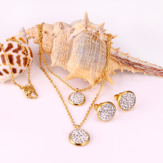 Gold plated stainless steel jewelry set with two layered necklaces and matching stud earrings. Features round crystal-studded pendants.