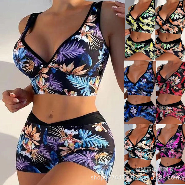 Two-piece swimsuit with a black background and vibrant pink and purple tropical floral print. Features a V-neck crop top and high-waisted boxer shorts.