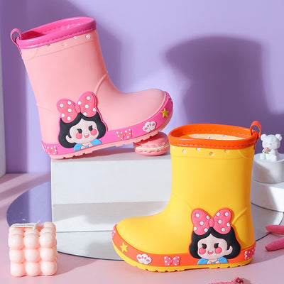 Bright yellow children's rain boots with a green cartoon dinosaur design and orange trim, held by hands. - Image 3