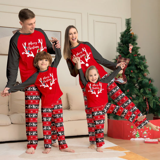 Family of four wearing matching red and black Christmas pajamas with a deer head and "Merry Christmas" print.