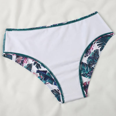 Teal twisted bandeau bikini top with tropical leaf print high-waisted bottoms on a model wearing a white shirt. - Image 20