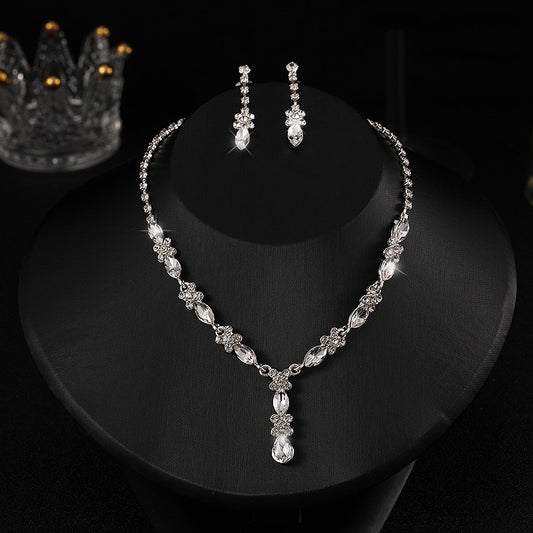 Elegant silver-tone necklace and matching drop earrings set with clear marquise and teardrop stones, displayed on a black bust.