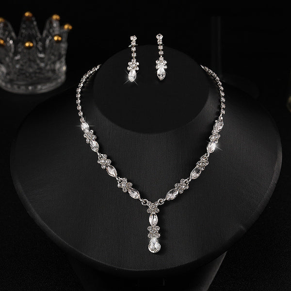 Elegant silver-tone necklace and matching drop earrings set with clear marquise and teardrop stones, displayed on a black bust.