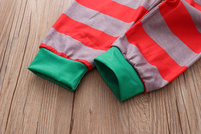 Family of five and pets wearing matching red and grey striped Christmas pajamas with Santa and penguin print. - Image 3