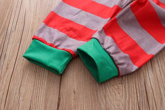 Family of five and pets wearing matching red and grey striped Christmas pajamas with Santa and penguin print. - Image 3