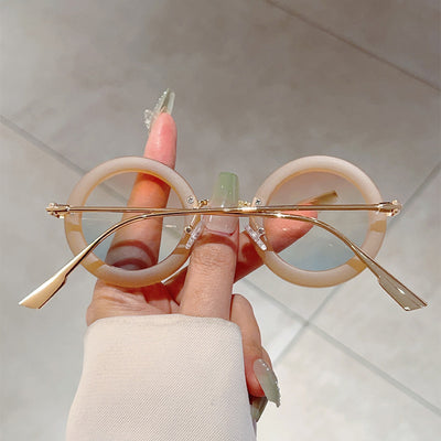 Small frame oval fashion sunglasses with black frames and vibrant orange lenses, held by a hand. - Image 19