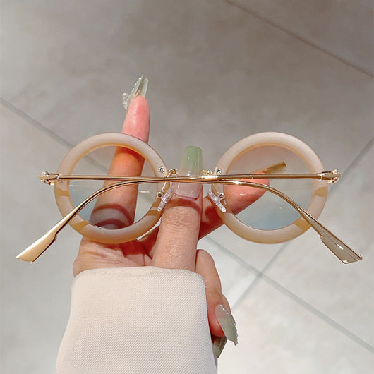 Small frame oval fashion sunglasses with black frames and vibrant orange lenses, held by a hand. - Image 19