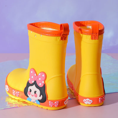 Bright yellow children's rain boots with a green cartoon dinosaur design and orange trim, held by hands. - Image 5