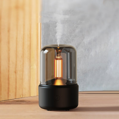 White cylindrical aroma diffuser with a clear top and an amber candlelight-effect LED light. - Image 5