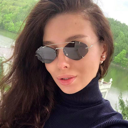 Metal frameless sunglasses for women with geometric gradient gray lenses and a silver-colored frame.