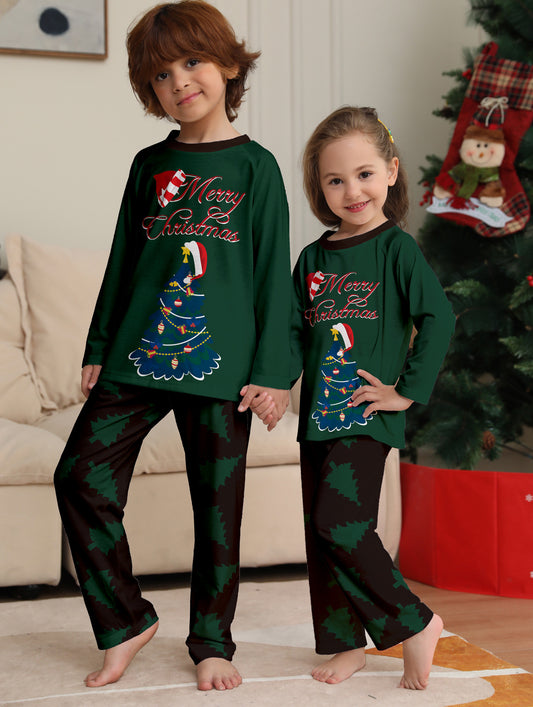 Young girl wearing a dark green long-sleeved Christmas pajama set with a decorated tree and "Merry Christmas" text. - Image 2