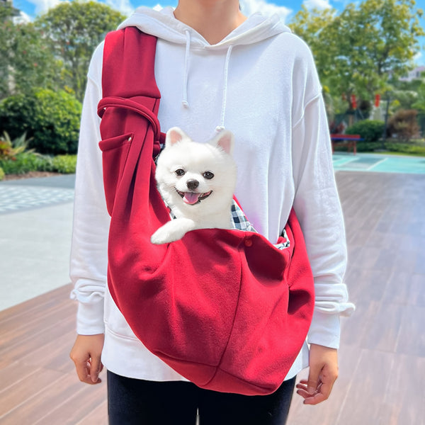 Person in white hoodie carrying a happy white dog in a navy blue pet sling bag outdoors. - Image 6